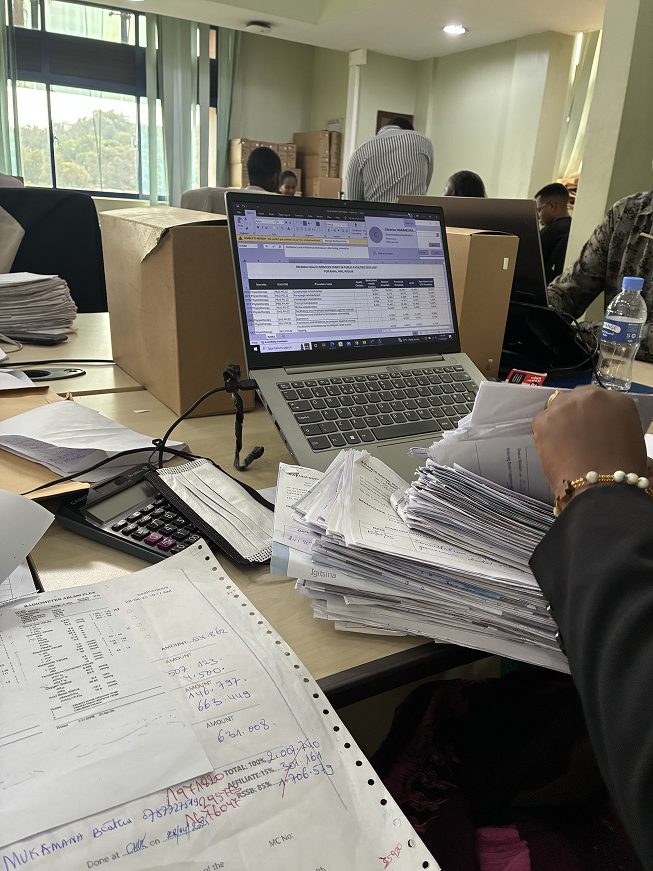 Field visit: voucher verification at a desk with a laptop and paperwork